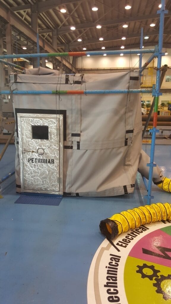 A worn-out vending machine labeled 'Cigarettes' in a cluttered industrial setting.