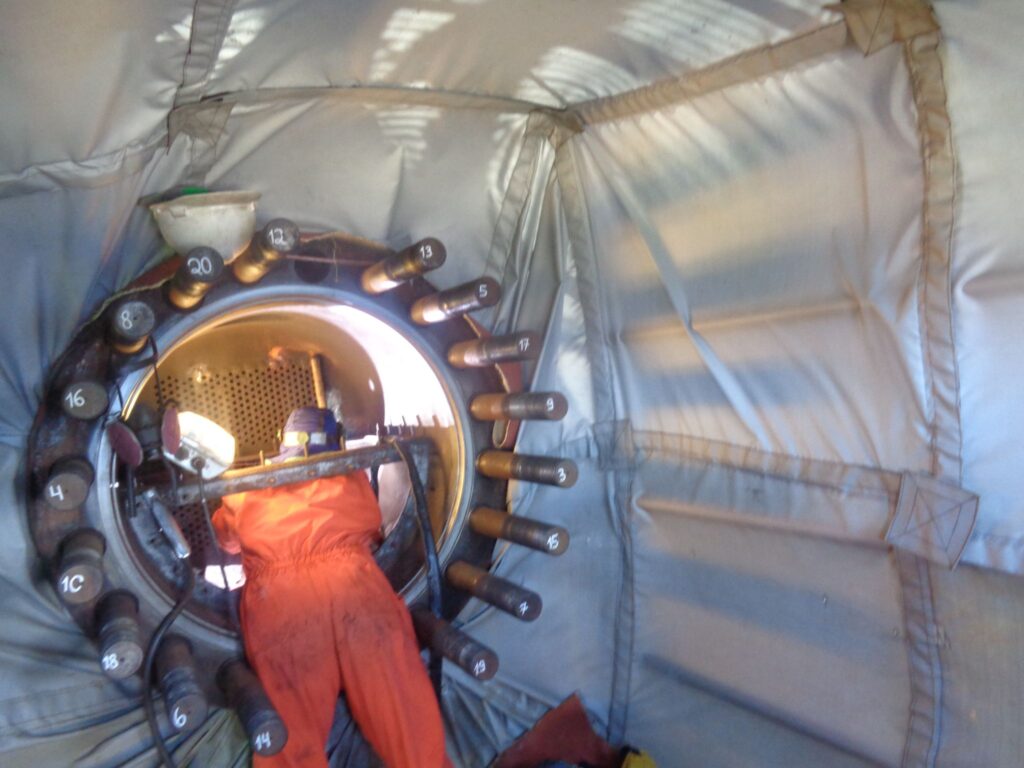Worker in orange suit inside a large industrial turbine or generator casing.